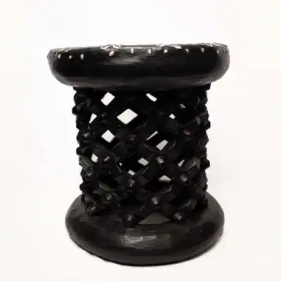 Taburete africano vintage de color negro: obra de arte de madera hecha a mano decorada con monedas y cauris disponible en Baobabmart